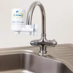 "فیلتر تصفیه آب شیر دلفین نصب‌شده روی شیر آشپزخانه با طراحی مدرن و بدنه سفید برند DOLPHIN"